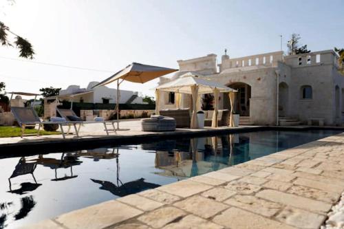 a swimming pool with chairs and a house at Villa Brachychiton in Ostuni