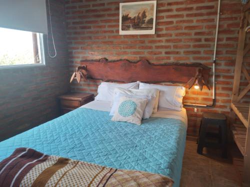 een slaapkamer met een bed met een bakstenen muur bij Cabañas Don Fernando in Santa Rosa de Calamuchita