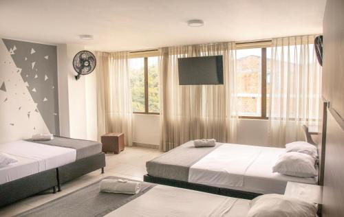 a bedroom with two beds and a flat screen tv at Hotel Inter del Café in Pereira