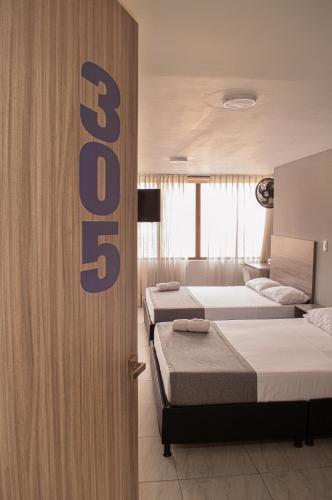 a bedroom with three beds and a sign that reads beds at Hotel Inter del Café in Pereira