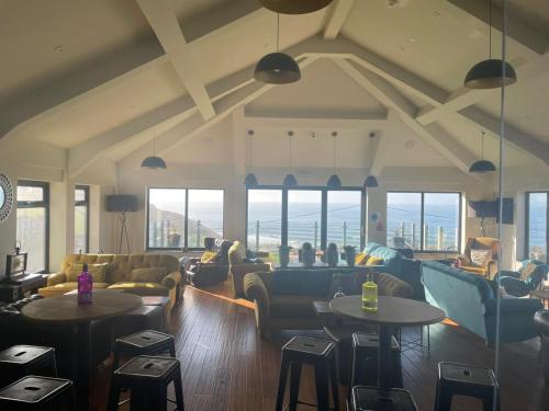 a living room with couches and tables and windows at Widemouth Manor in Bude