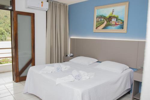 um quarto de hotel com uma cama com lençóis brancos em Hotel Termas do Lago em Gravatal