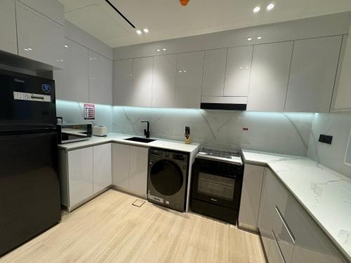a kitchen with white cabinets and a dishwasher in it at ASHRI HH, Luxurious Apt in JVC in Dubai