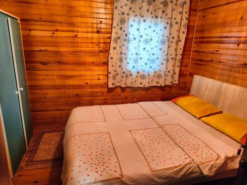 Cama en habitación de madera con ventana en Bungalow with Garden and Air Conditioning, 150m to the Sea in Bademli, Sleeps 6, en Dikili