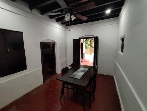 a dining room with a table and a ceiling fan at Sukūn Heritage -A traditional 4 Bedroom Vacation Villa in Kannur