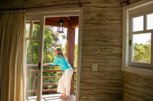 a woman standing on a porch looking out of a door at ApartCasa completo para até 4 próx. Templo Budista in Três Coroas