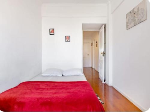 a white bedroom with a red blanket on a bed at Rigoli House in Lisbon