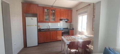a kitchen with wooden cabinets and a table and a white refrigerator at Vivienda Vacacional Casa Paulina in Punta del Hidalgo