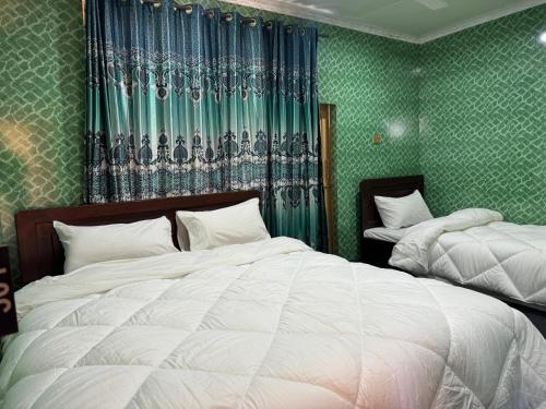 a bedroom with two beds and green wallpaper at Heaven Hotel Skardu in Skardu