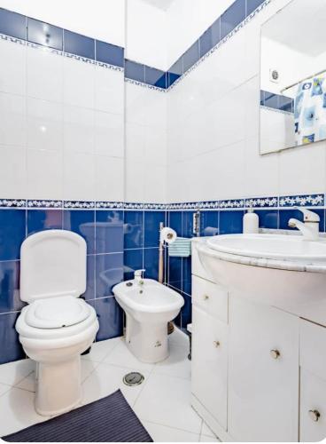 a blue and white bathroom with a toilet and a sink at Rigoli House in Lisbon