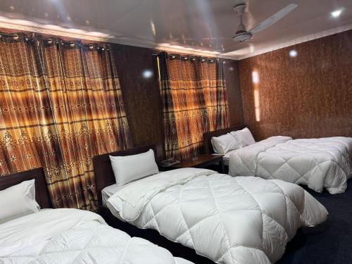 a hotel room with three beds and curtains at Heaven Hotel Skardu in Skardu