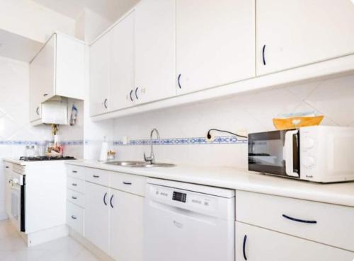a white kitchen with white cabinets and a microwave at Rigoli House in Lisbon