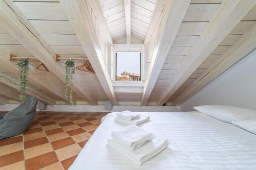 a attic bedroom with a bed with white sheets and a window at Kenova Apartments Old Town in Dubrovnik
