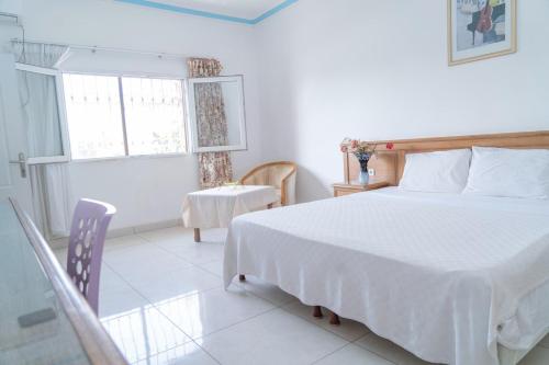 1 dormitorio con cama, mesa y ventana en Hotel Azur Conakry en Conakry