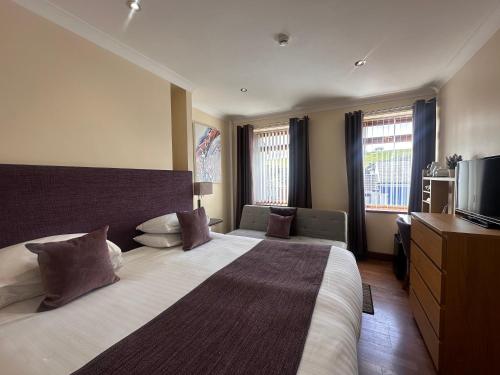 a hotel room with a large bed and a television at The Bell Guesthouse in Peterlee