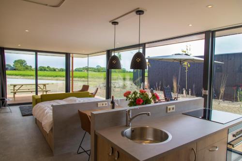 uma cozinha com um lavatório e uma sala de estar com uma cama em Buiten Pekelinge em Oostkapelle