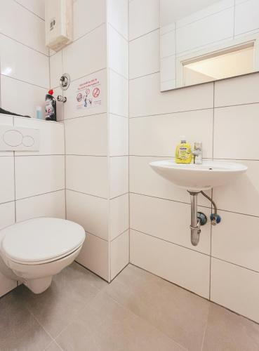 ein weißes Bad mit einem WC und einem Waschbecken in der Unterkunft Home4Now DOR02 Gemütliche Monteursunterkunft in Dormagen in Dormagen
