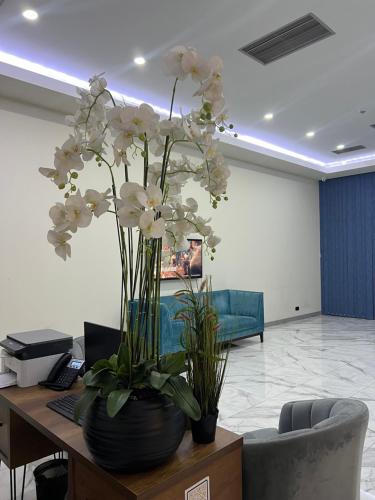 a vase of white flowers on a desk in an office at Orbi City HOTEL in Batumi