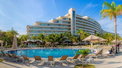 un complejo con piscina, sillas y un edificio en Palacio Mundo Imperial Riviera Diamante Acapulco All Inclusive, en Acapulco