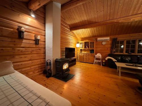 a bedroom with a fireplace in a room with wooden walls at Traditional Norwegian log cabin with sauna by the sea in Tornes