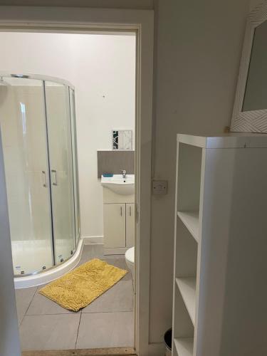 uma casa de banho com um chuveiro e um tapete amarelo em KGA4 - Kazi Court em Wakefield