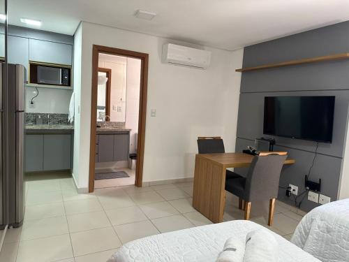 um quarto com uma secretária e uma cozinha com uma televisão em Studio 606 - Expetacular em Ribeirão Preto