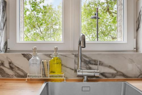 a kitchen sink with a faucet and two windows at Luxury Flat by Les Maisons de Charloc Homes in Paris