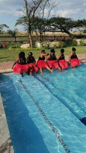 a group of women in dresses sitting in a swimming pool at Elias Nefale Eco Estate in Mitxetweni