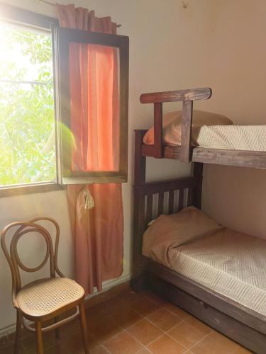 a room with bunk beds and a chair and a window at Casa Ciao in Deán Funes