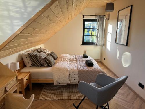 a attic bedroom with a bed and a chair at Willa na szlaku in Stronie Śląskie