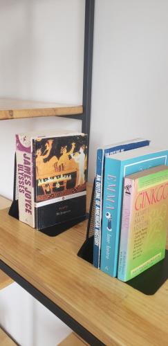 three books sitting on top of a wooden shelf at Pomegranates & Olives Guesthouse in Durrës