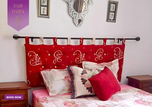 a bed with a red headboard and pillows on it at Verte Casa in Hammamet
