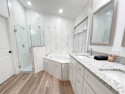 a white bathroom with two sinks and a shower at The Sanford Ave House with fully fenced yard in Sanford