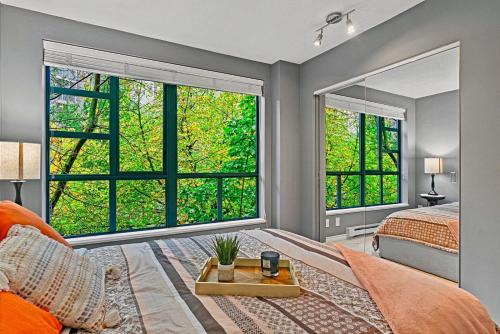 a bedroom with a bed and two large windows at Stunning 3 Bedroom Duplex in the heart of Yaletown! Sleeps 8 in Vancouver