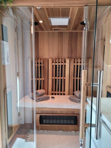 een douche in een kamer met houten wanden bij Tiny Villa de Haas met Infraroodsauna in Egmond aan Zee
