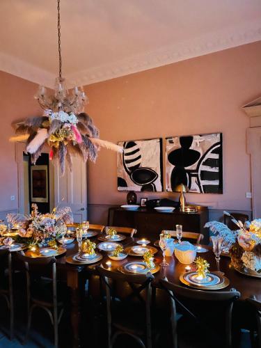 a dining room with a table with chairs and a chandelier at Norfolk House Hosted by The Scarlet Hen in Huddersfield