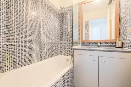 une salle de bain avec une baignoire, un lavabo et un miroir dans l'établissement Résidence le Hameau de Cap Esterel - maeva Home - Appartement 2 pièces 7 personnes - Sélection MAE-7954, à Saint-Raphaël