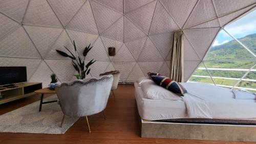 un soggiorno con letto e una grande finestra di Syameen's Glamping Dome a Kampong Kundassan
