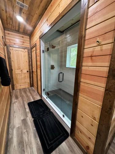 a bathroom with a glass shower in a wooden cabin at The New Romantic Moonlight Dream Cabin! in Broken Bow