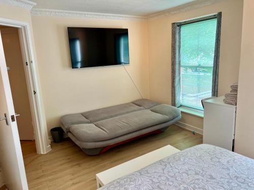 a bedroom with a dog bed and a flat screen tv at Coco’s Homestay - Sidmouth in Reading