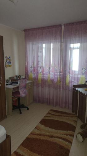 1 dormitorio con escritorio y ventana con cortinas en Cris confort, en Fălticeni