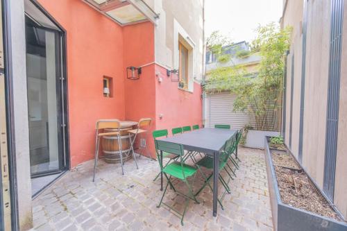 un patio avec une table et des chaises devant un bâtiment dans l'établissement Le Royaume - Parking, à Reims