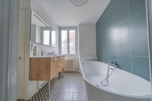 une salle de bain avec une baignoire, un lavabo et un miroir dans l'établissement Le Royaume - Parking, à Reims