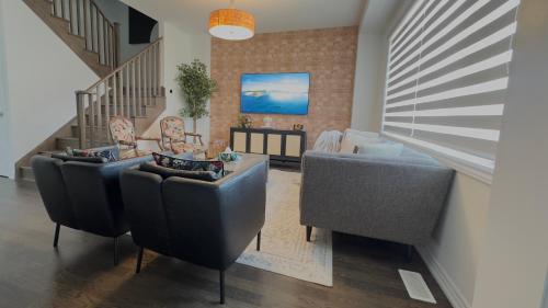 ein Wohnzimmer mit Sofas und Stühlen sowie eine Treppe in der Unterkunft Modern 3BR Home close to NiagaraFalls with Parking in Thorold
