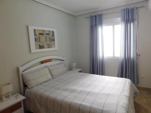 a bedroom with a white bed and a window at Playamarina I in Cabo Roig