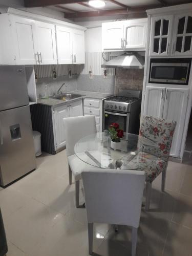 eine Küche mit weißen Schränken sowie einem Tisch und Stühlen in der Unterkunft Nido de Amor in Pantoja