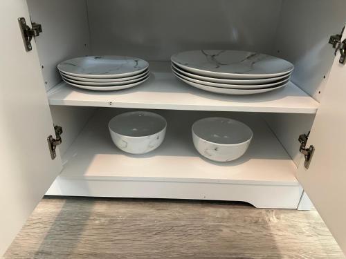 a cupboard with plates and bowls in it at Luxury en-suite rooms in Southampton