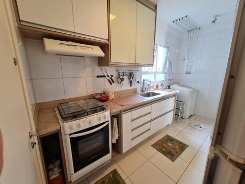 a small kitchen with a stove and a sink at Apartamento Aconchegante in Ribeirão Preto