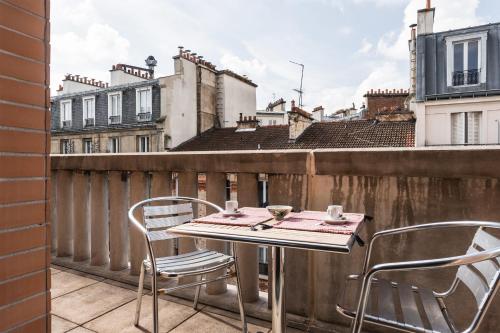une table et des chaises sur un balcon avec vue dans l'établissement Appartement du Théâtre - Welkeys, à Paris