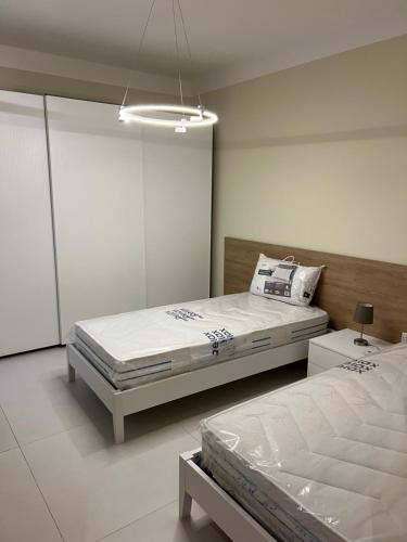 a white bedroom with two beds and a lamp at Superb 3 Bedroom Apartment in Gzira Promenade in Il-Gżira
